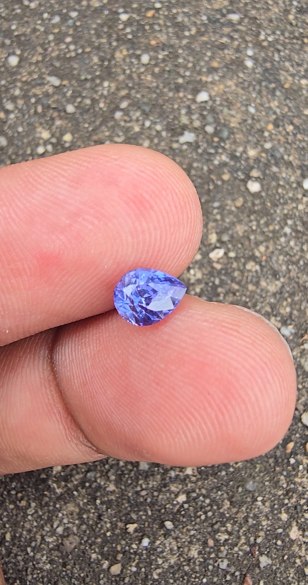 Lavender violet pear-shaped sapphire positioned sideways on fingertips